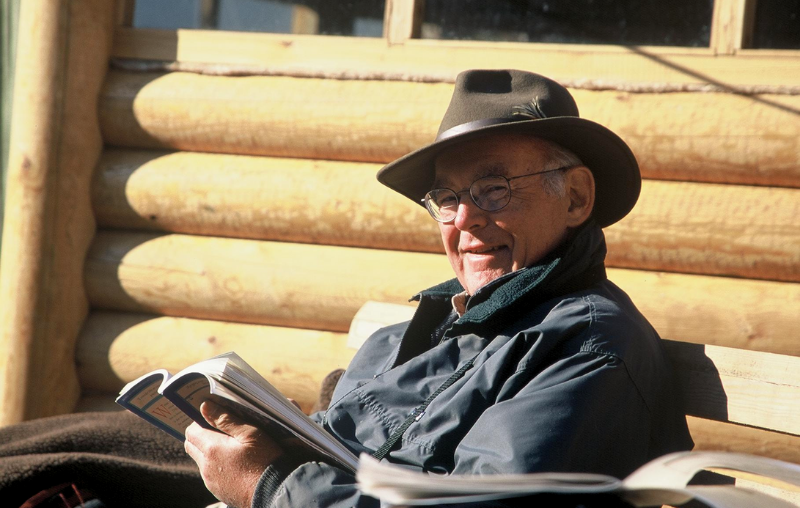 Gordon smiling with his hat on reading a book